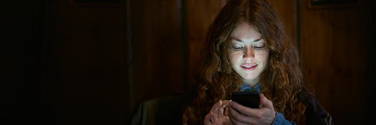 Frau schaut auf Handy, scrollt durch Dating-Profile 