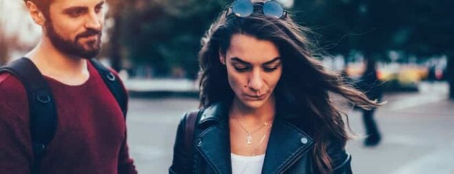 Mann und Frau stehen unglücklich nebeneinander weil die Beziehung durch einen Trennungsgrund kaputt gegangen ist