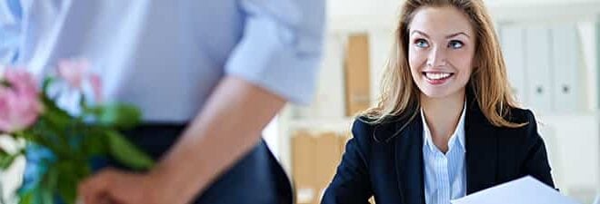 Flirten am Arbeitsplatz - Mann schenkt Frau Blumen