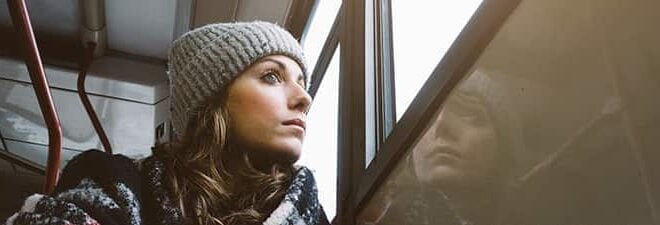 Frau sitzt in der Bahn, schaut aus dem Fenster und fragt sich "Vermisst er mich?"