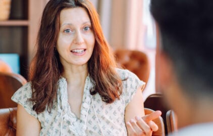 Eine Frau mit rot-brauen Haaren unterhält sich mit einem Mann
