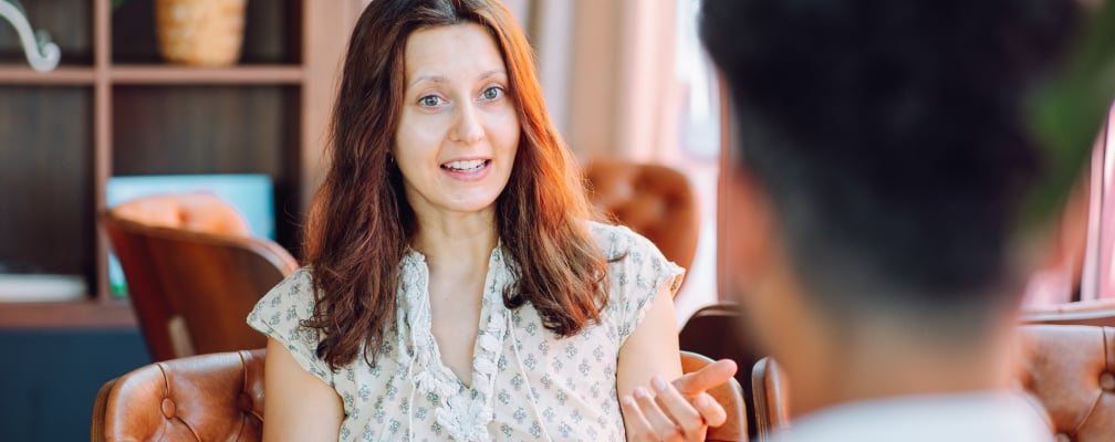 Eine Frau mit rot-brauen Haaren unterhält sich mit einem Mann