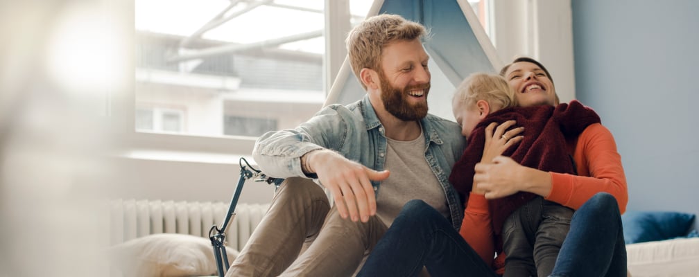 Eine lachende Familie mit einem kleinen Kind im Arm.